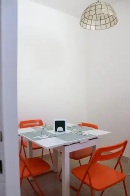 a white table with orange chairs and a laptop on it at Dimora Trasteverina Holiday Home in Rome