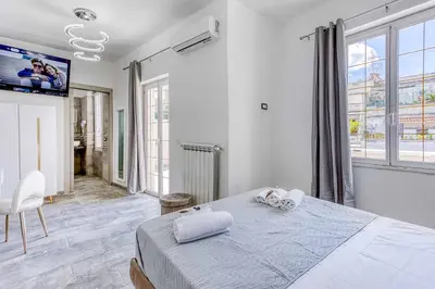 a white bedroom with a bed and a tv at ARDECORE VIA VIGEVANO Guest House o Affittacamere in Rome