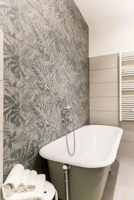 a bathroom with a white tub and a tropical wallpaper at Top Location - walk to Navona Pantheon and Vatican in Rome