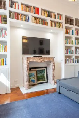 a living room with a fireplace with books at Suite Elizabeth in Barberini in Rome