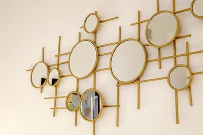 a group of gold mirrors hanging on a wall at Santaluna in Rome