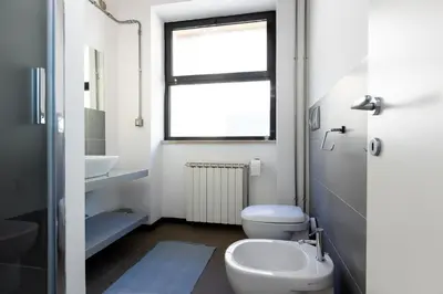 a bathroom with a toilet and a sink and a window at Loft Ostiense Blue in Rome