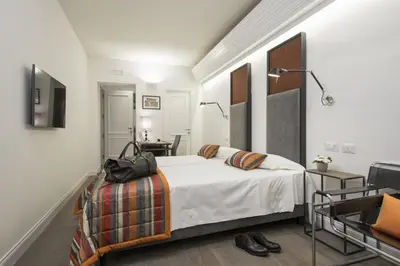 a white bedroom with a bed and a desk at Maison Evelina in Rome