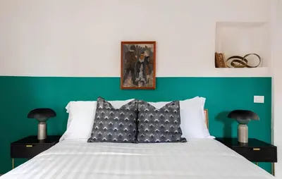 a bedroom with a white bed with a green wall at Historic 3BR Colosseum Apartment 160sqm for 9 in Rome