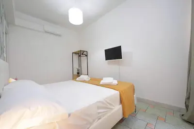 a white bedroom with two beds and a tv at Domus Sinuessa in Rome