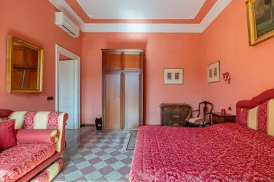 a bedroom with pink walls and two beds and a couch at Residenza Episcopo Lipinsky 1902 in Rome