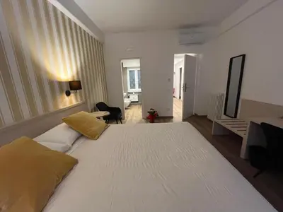 a bedroom with a large white bed and a living room at MARITZA Guest House 2 in Rome