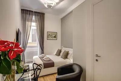 a bedroom with a bed and a chair and a window at Orange Suites in Rome