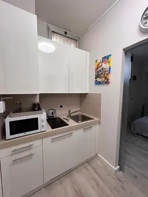a kitchen with white cabinets and a sink and a microwave at Charme Holidays San Saba in Rome