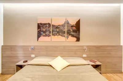 a bed in a room with three paintings on the wall at Vatican Rooms Cipro in Rome