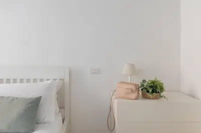 a white bedroom with a bed with a lamp and a plant at iFlat Monti Charming & Cozy Apt by the Colosseum in Rome