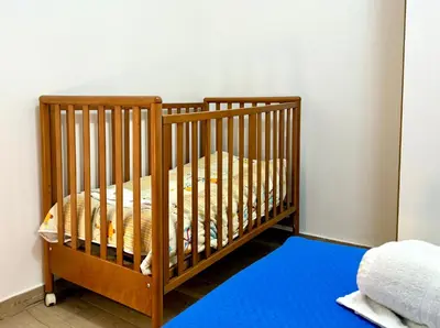 a crib in a room with a blue rug at Domus Basilica San Paolo in Rome