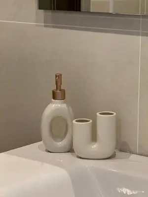 a bottle of soap and two cups on a bathroom sink at Giorgi House in Rome