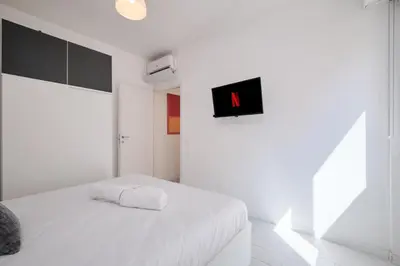 a bedroom with a white bed and a tv on the wall at Apt at Tiburtina Station Free WiFi e Netflix in Rome