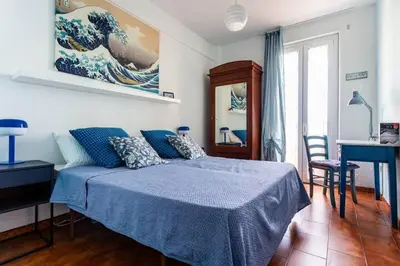 a bedroom with a blue bed and a desk and a table at Appartamento con balcone a San Giovanni, piano alto con vista su Roma in Rome
