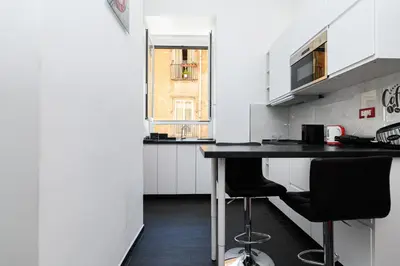 a kitchen with a black counter and two chairs at Casetta di quartiere Roma in Rome