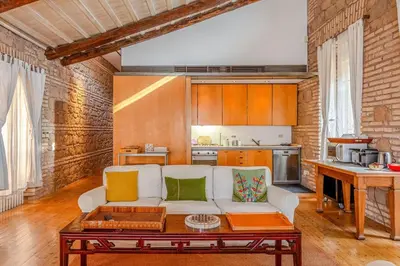 a living room with a white couch and a kitchen at The Loft Boutique Apartment Vatican Museum in Rome