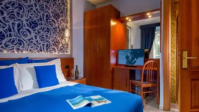 a bedroom with a blue bed with a book on it at IN Roma Vale&Hillary colosseo b&b in Rome