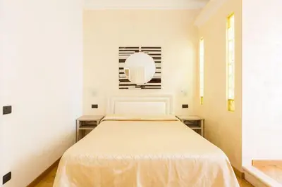a white bedroom with a bed and a mirror at Relais Calamatta in Rome