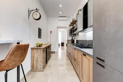 a kitchen with wooden cabinets and a clock on the wall at FaMa - Mecenate 3BR & 2BA in Rome