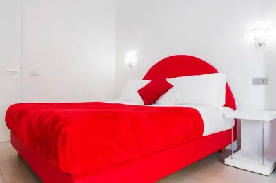 a red bed with white pillows and a red headboard at Vatican Grand Suite in Rome
