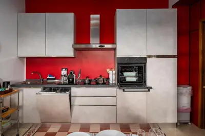 a kitchen with white cabinets and a red wall at Piazza Vittorio Urban Stay in Rome