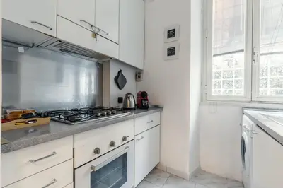 a kitchen with white cabinets and a stove top oven at San Pietro Apartment Vatican 5 min Walk in Rome
