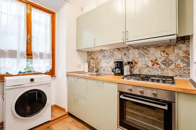 a kitchen with white cabinets and a washer and dryer at Colosseo Comfort e Stile in centro a Roma in Rome