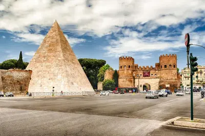 a building with a pyramid and cars in a street at PIRAMIDE apartment in Rome
