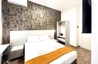 a bedroom with a white bed and a stone wall at Qg Golden Rooms in Rome
