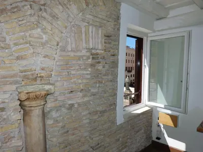 a stone wall in a room with a window at The column of Campo de' Fiori in Rome