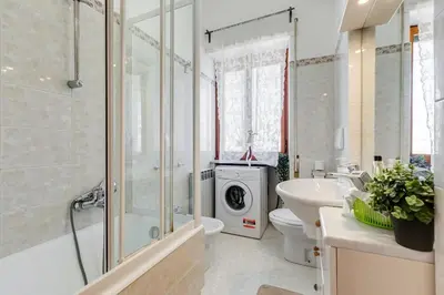 a bathroom with a sink toilet and a washing machine at Karolina's Home, 2-BDR at Vatican in Rome