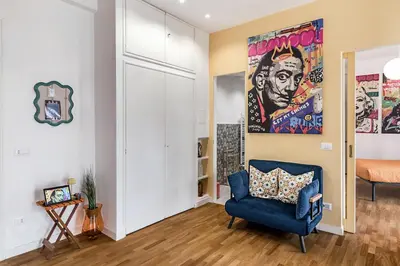 a living room with a blue chair and a painting on the wall at Lungotevere Bijou with Private Balcony in Rome