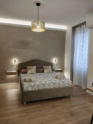 a bedroom with a large bed and a chandelier at Metro Re di Roma Apartment in Rome