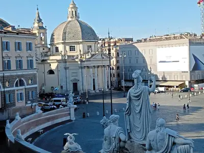 a statue in the middle of a city with buildings at Roman Babuino Inn in Rome