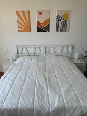 a white bed in a bedroom with paintings on the wall at La Casa di Bru - Cinque Camere - Dieci posti - Terrazzo in Rome