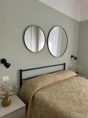 two mirrors above a bed in a bedroom at Rhome Holiday Home Casal Bertone in Rome
