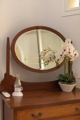 a mirror on top of a wooden dresser with flowers at Dimora Conti in Rome