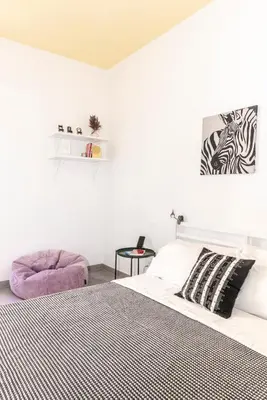 a white bedroom with a bed and a purple chair at Casa Chiagio in Rome