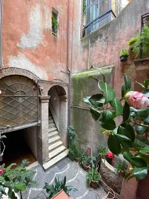 a courtyard of a building with stairs and plants at Arco Acetari - The Middle Ages in the heart of Rome in Rome