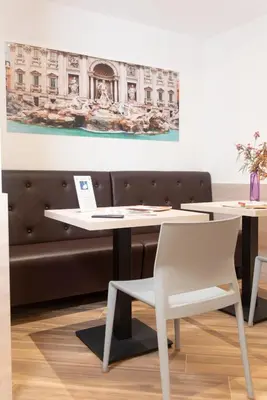 a table with a white chair and a painting on the wall at Chessa's Rooms in Rome