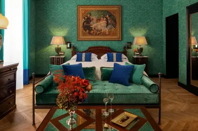 a bedroom with a bed and a green couch at Hotel d’Inghilterra Roma – Starhotels Collezione in Rome