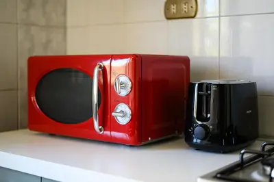a red microwave sitting on a counter next to a toaster oven at NEW Diana's place with terrace San Pietro Station in Rome