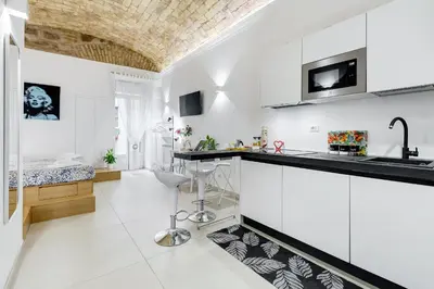 a kitchen with white cabinets and a black counter top at Vatican Scipioni Charming Studio relaxing and patio in Rome