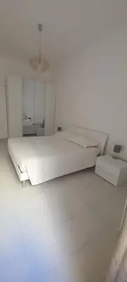 a white bedroom with a large bed and a table at Alessandro's Home in Rome