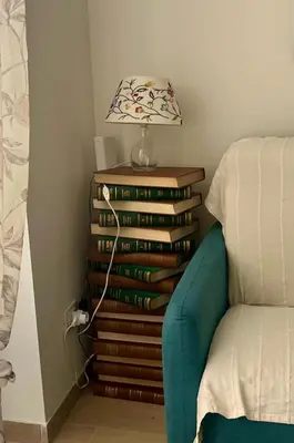 a lamp on top of a stack of books next to a couch at Il Pianoforte di Teresa - appartamento a Monteverde in Rome