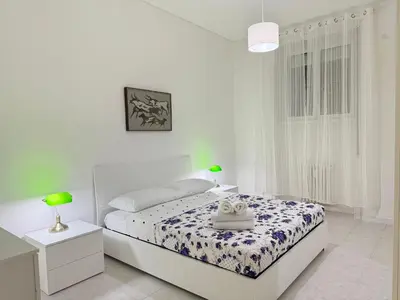 a white bedroom with a bed and two night stands at Always Home in Rome