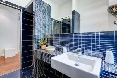 a blue tiled bathroom with a sink and a mirror at Luxury Ludo House Trastevere in Rome