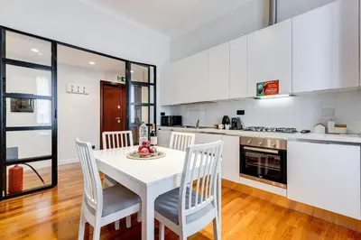 a white kitchen with a white table and chairs at Luxury Ludo House Trastevere in Rome