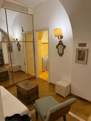 a living room with a bed and a chair and a mirror at La casetta nel vicolo in Rome
